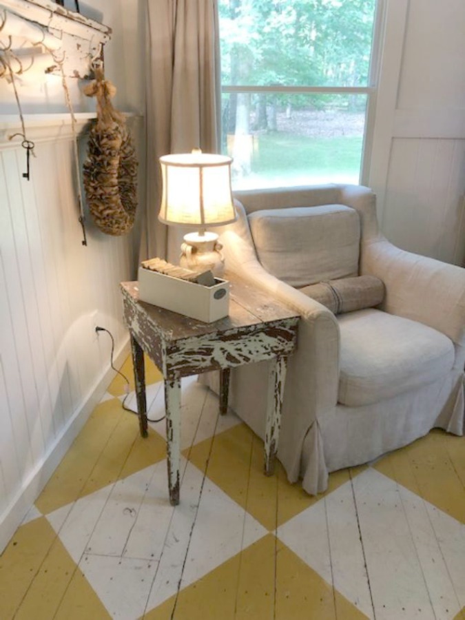 Farmhouse chic living room with vintage treasures, bold yellow painted poplar wood flooring, linen upholstery, and design by City Farmhouse for Storybook Cottage in Leiper's Fork, TN - Hello Lovely Studio. #farmhousestyle #livingroom #cityfarmhouse #storybookcottage