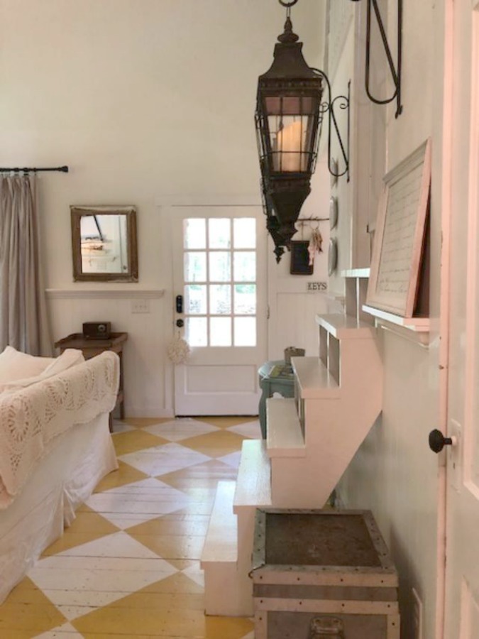 Farmhouse chic living room with vintage treasures, bold yellow painted poplar wood flooring, linen upholstery, and design by City Farmhouse for Storybook Cottage in Leiper's Fork, TN - Hello Lovely Studio. #farmhousestyle #livingroom #cityfarmhouse #storybookcottage