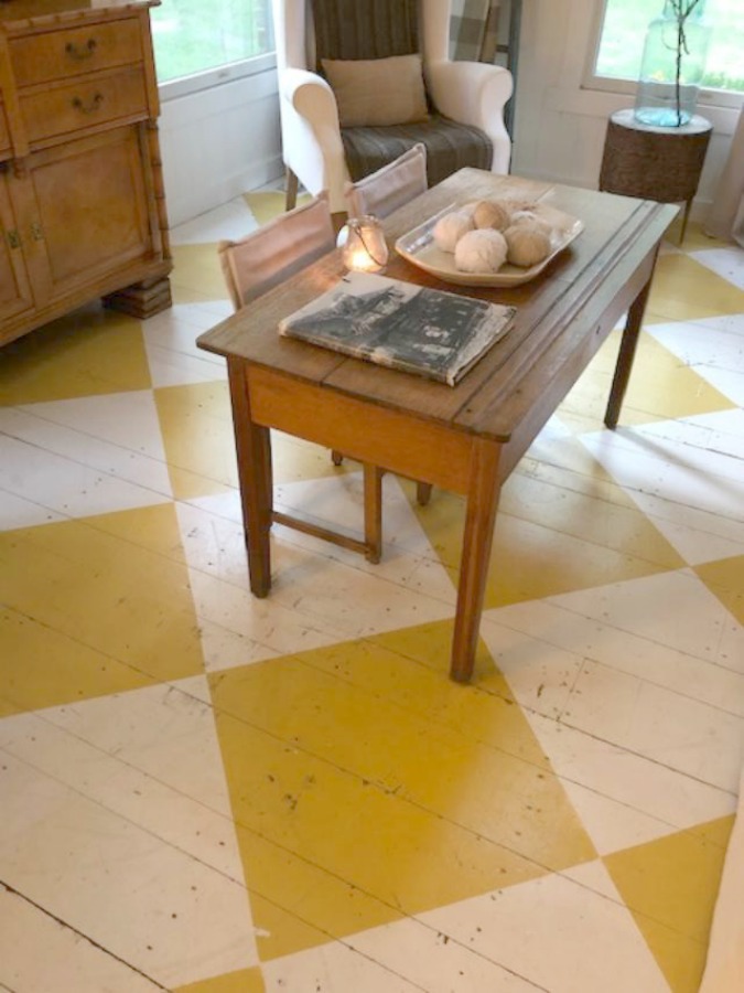 Farmhouse chic living room with vintage treasures, bold yellow painted poplar wood flooring, linen upholstery, and design by City Farmhouse for Storybook Cottage in Leiper's Fork, TN - Hello Lovely Studio. #farmhousestyle #livingroom #cityfarmhouse #storybookcottage