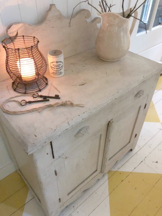 Farmhouse chic living room with vintage treasures, bold yellow painted poplar wood flooring, linen upholstery, and design by City Farmhouse for Storybook Cottage in Leiper's Fork, TN - Hello Lovely Studio. #farmhousestyle #livingroom #cityfarmhouse #storybookcottage