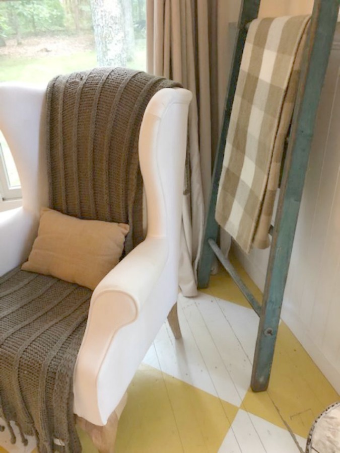 Farmhouse chic living room with vintage treasures, bold yellow painted poplar wood flooring, linen upholstery, and design by City Farmhouse for Storybook Cottage in Leiper's Fork, TN - Hello Lovely Studio. #farmhousestyle #livingroom #cityfarmhouse #storybookcottage