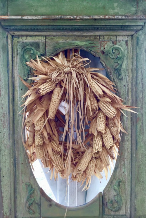 A charming dried corn cob wreath on a door in autumn by Marsha Smith - Cottonseed Trading Company. #falldecor #fallwreath #corncob #wreaths