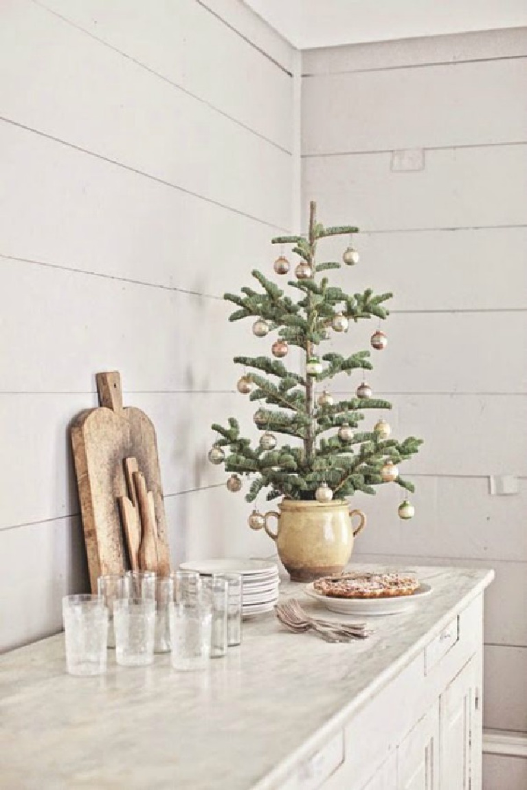 French farmhouse Christmas decor vignette on a buffet with whimsical fresh tree, vintage cutting boards, and white shiplap - Dreamywhites.