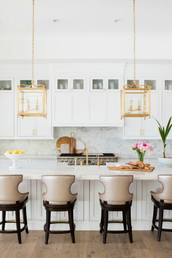 Airy and bright white kitchen with brass lantern pendants over island in a modern French home in Queen Creek, AZ. #modernfrench #kitchendesign #brasspendant