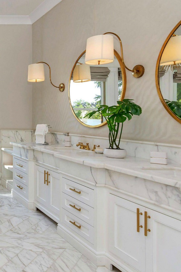 Luxurious bath design with marble, white cabinetry, and brass hardware in a modern French home in Queen Creek, AZ. #bathroomdesign #luxurious #whitemarble #modernFrench