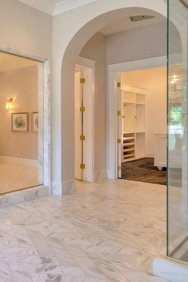 Luxurious bath design with marble, white cabinetry, and brass hardware in a modern French home in Queen Creek, AZ. #bathroomdesign #luxurious #whitemarble #modernFrench