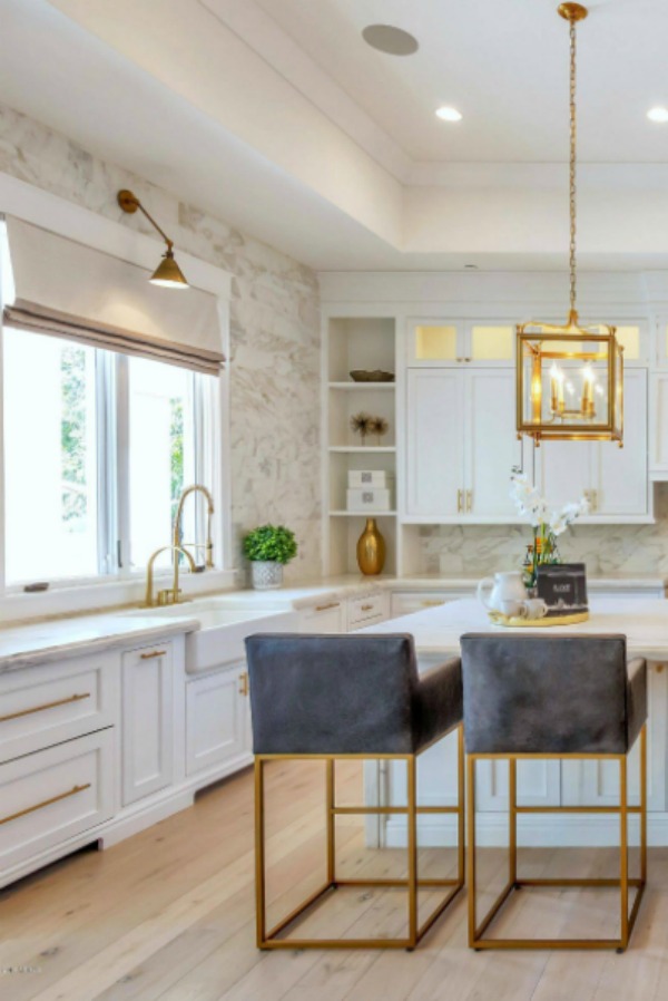 Breathtaking white kitchen with farm sink and large island with brass hardware in modern French home. #interiordesign #kitchendesign #modernfrench #whitekitchen