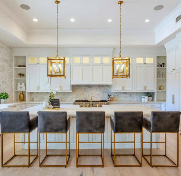 Breathtaking white kitchen with farm sink and large island with brass hardware in modern French home. #interiordesign #kitchendesign #modernfrench #whitekitchen