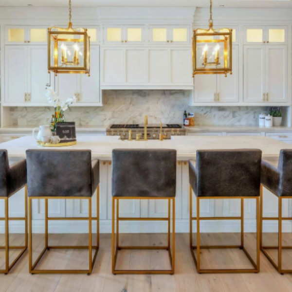 Breathtaking white kitchen with farm sink and large island with brass hardware in modern French home. #interiordesign #kitchendesign #modernfrench #whitekitchen