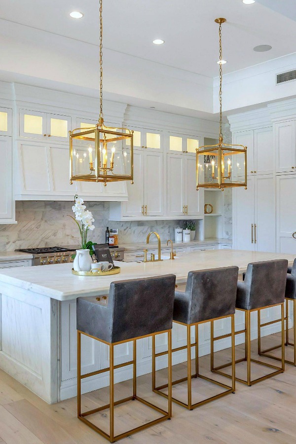 Breathtaking white kitchen with farm sink and large island with brass hardware in modern French home. #interiordesign #kitchendesign #modernfrench #whitekitchen