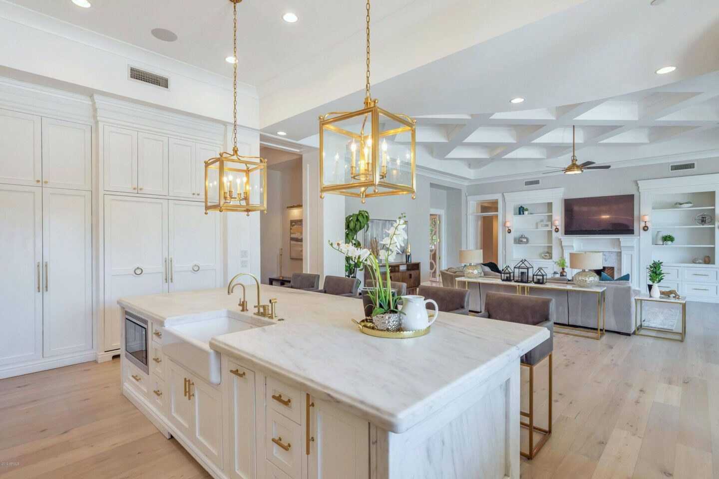 Breathtaking white kitchen with farm sink and large island with brass hardware in modern French home. #interiordesign #kitchendesign #modernfrench #whitekitchen