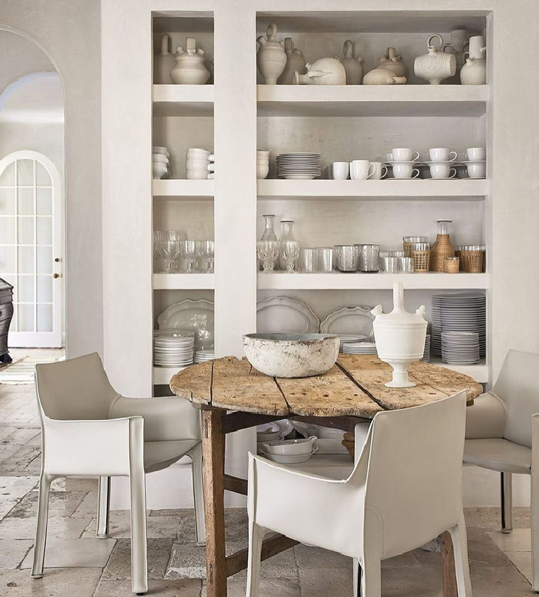 Breathtaking white modern French breakfast dining area with shelves, farm table, and modern chairs - interior design by Pamela Pierce. #pamelapierce #modernfrench #allwhitedecor #frenchcountry