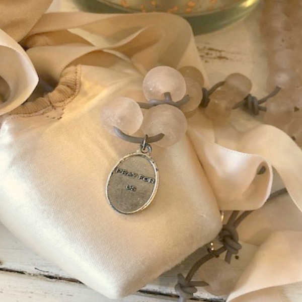 Pale pink pointe shoes and glass bead necklace in a soft pastel fall vignette.