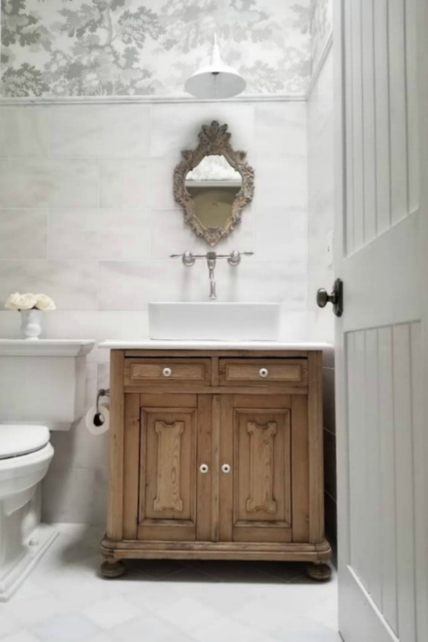 White French country bathroom with natural wood vanity and understated French country decor - The French Nest Co. #frenchcountry #interiordesign #whitebathroom #rusticelegance
