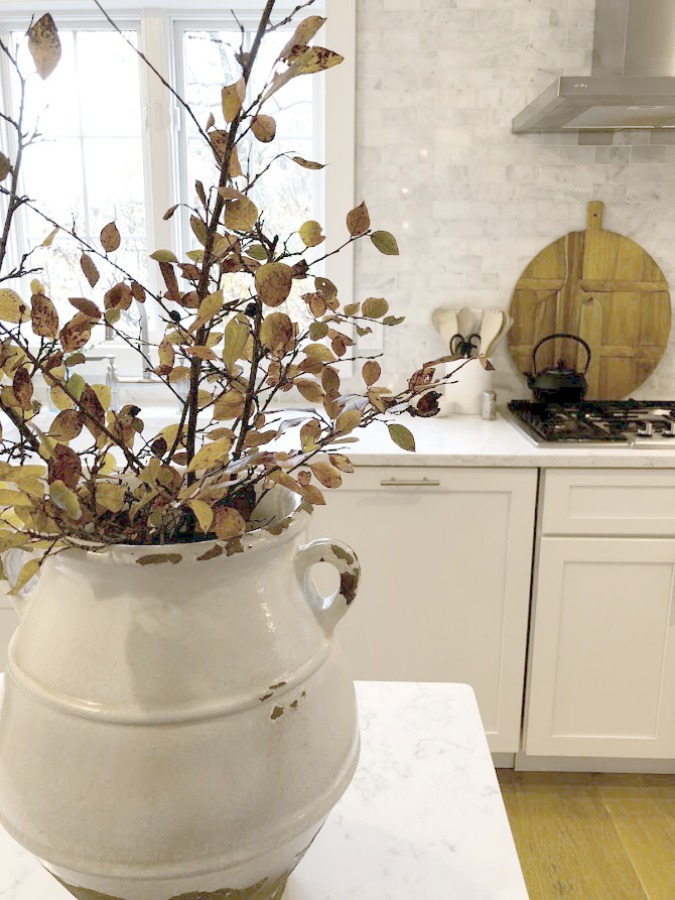 Shaker style white cabinets in simple serene kitchen with white oak floors and Viatera Minuet quartz countertops - Hello Lovely Studio.