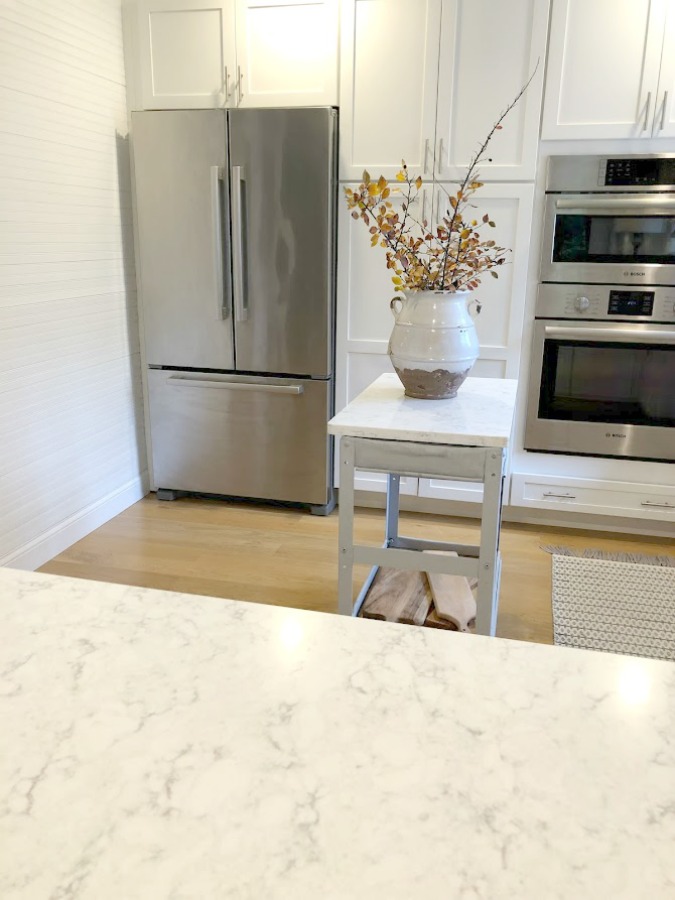 Shaker style white cabinets in simple serene kitchen with white oak floors and Viatera Minuet quartz countertops - Hello Lovely Studio.