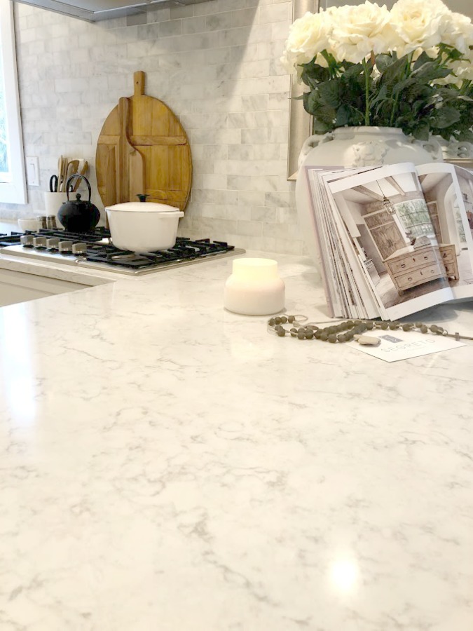 Shaker style white cabinets in simple serene kitchen with white oak floors and Viatera Minuet quartz countertops - Hello Lovely Studio.