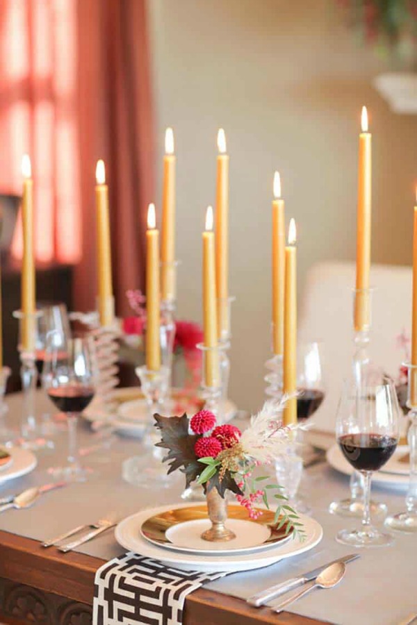 Gorgeously styled Thanksgiving table setting idea with gold toned candles, pink flowers, and crystal candleholders - Camille Styles. #thanksgiving #tablescape #tablesetting #placesetting