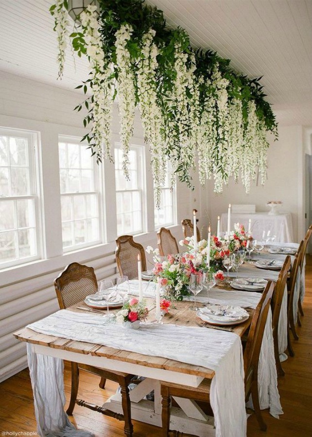 Romantic and lovely fall tablescape from Holly Chapple with suspended branches on ceiling and rustic white farm table. #thanksgiving #falltable #tablescape #tablesetting #romantic #whitefarmhouse