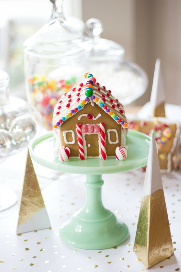 Sweet and petite simple gingerbread house cottage upon a jadeite cake pedestal - Design Improvised. #gingerbreadhouse #christmasdiy #holidaybaking