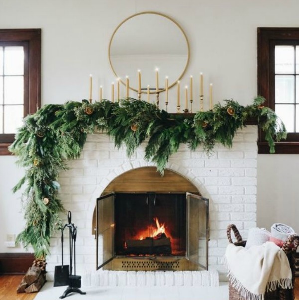 Beautiful faux evergreen garland on white brick holiday fireplace - Francoi et Moi. #fireplace #manteslcape #holidaydecor #garland