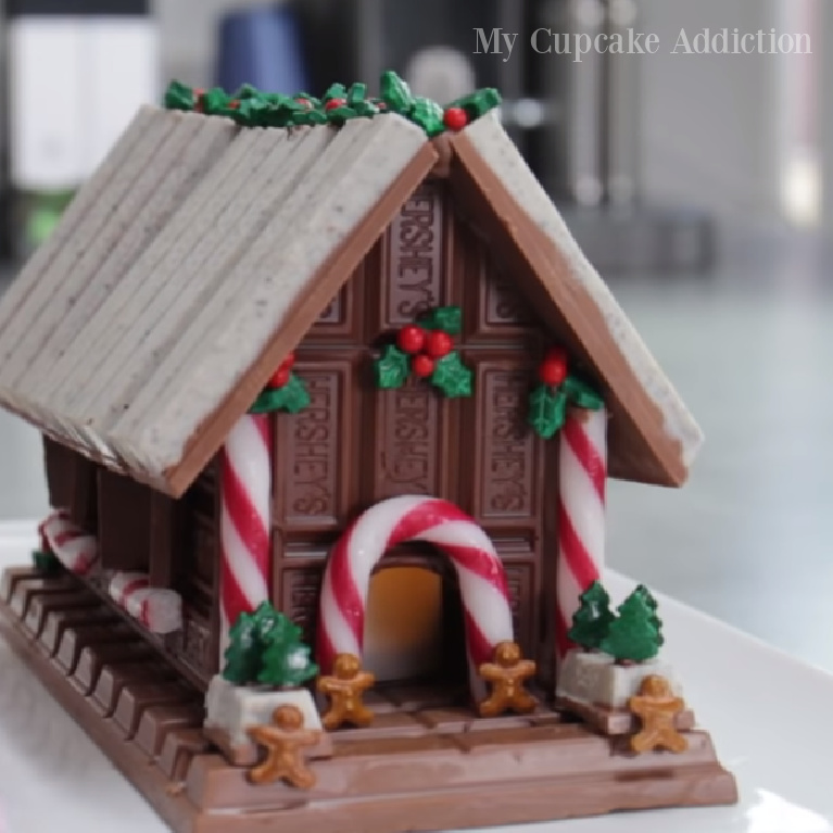 Chocolate bar candy gingerbread house with Kitkat and Hershey - MyCupcakeAddiction. #gingerbreadhouses #christmasbaking #candyhouses #chocolatehouses #chocolatelovers #holidaybaking #holidaycrafts