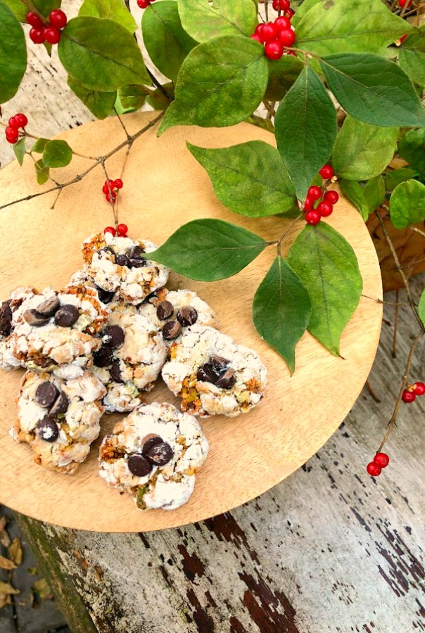 Pistachio Almond Crinkle Cookies on a Wood Pedestal - Hello Lovely Studio. #hellolovelystudio #cookierecipe #pistachio