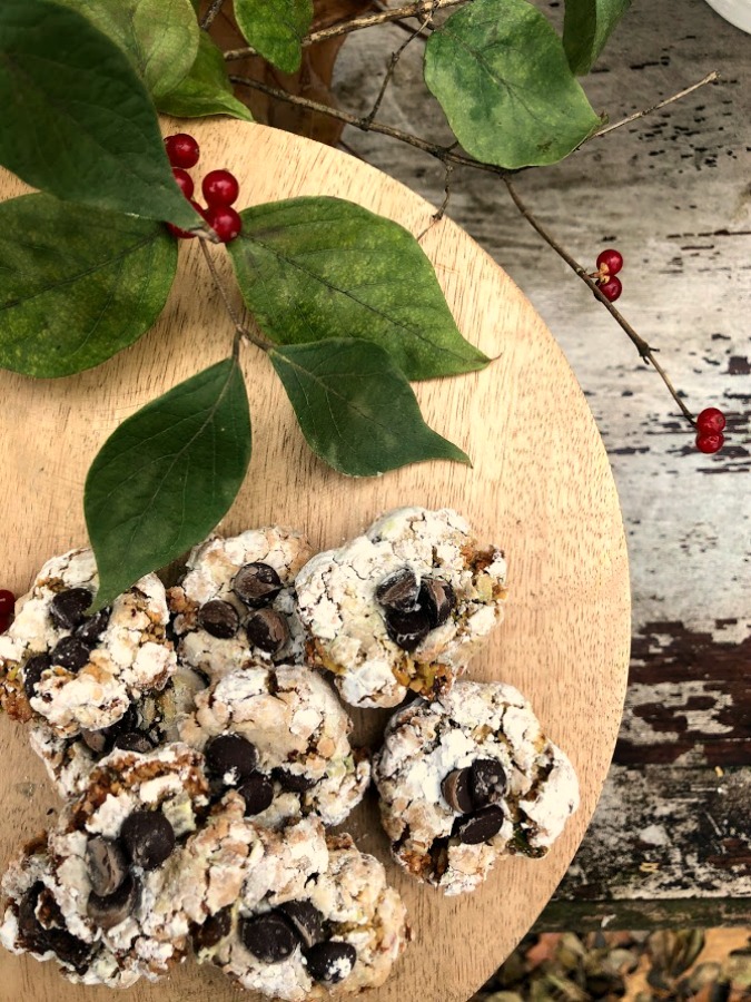 Pistachio Almond Crinkle Cookies on a Wood Pedestal - Hello Lovely Studio. #hellolovelystudio #cookierecipe #pistachio