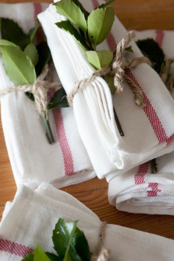 Simple red and white napkins tied with twine and greenery for a holiday tablescape - Ikea. #holidaytable #tablescapes #christmasdecor