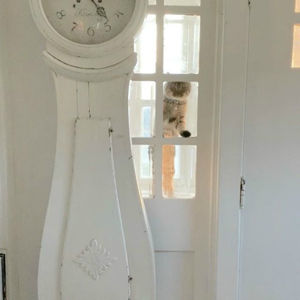 White Swedish Mora clock in a lovely vintage Swedish farmhouse with a cat at the glass door - My Petite Maison.