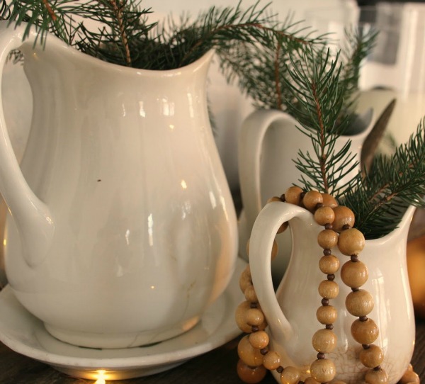 White Christmas decorated ironstone pitchers with fresh greenery in my home - Hello Lovely Studio. #hellolovelystudio #ironstone #christmasdecor