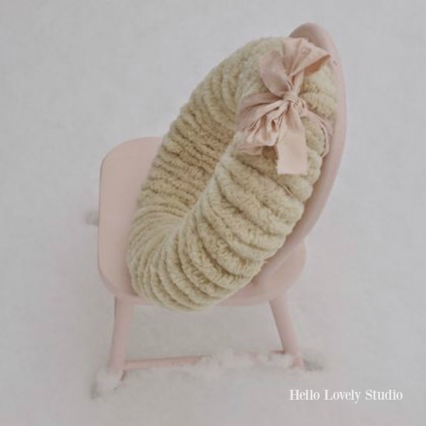 Jolie petite chaise rose dans la neige avec une couronne de pompons de Noël - Hello Lovely Studio. #christmasdecor #pompomwreath #christmaswreath #pinkchristmas