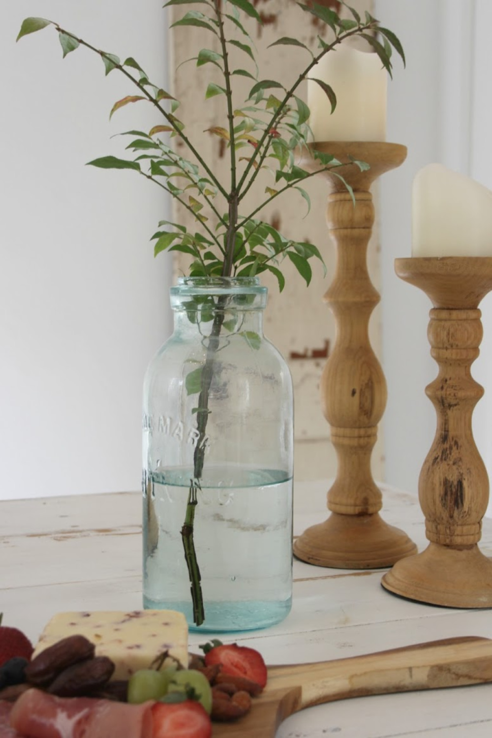 Hello Lovely Studio serene vignette with branch and rustic candle holders. Come score ideas for a Timeless and Tranquil European Country Inspired Look. #europeancountry #interiordesign #frenchcountry