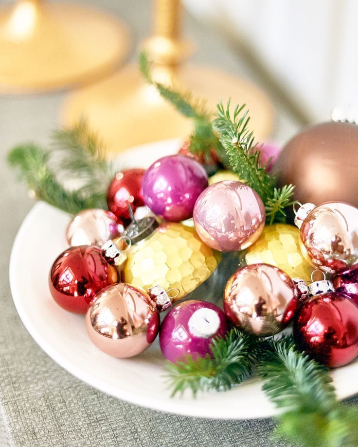 Colorful Christmas ornament bulbs with fresh greenery in a simple white bowl for an elegant vignette at Atlanta Home for the Holidays Showhouse.