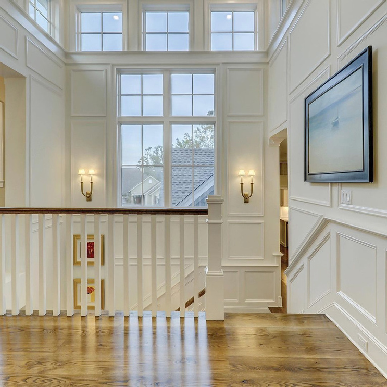 Benjamin Moore Simply White painted paneling and trim in a beautiful traditional stairway landing - Susan Joyce Design. #simplywhtie #benjaminmooresimplywhite #whitepaintcolors