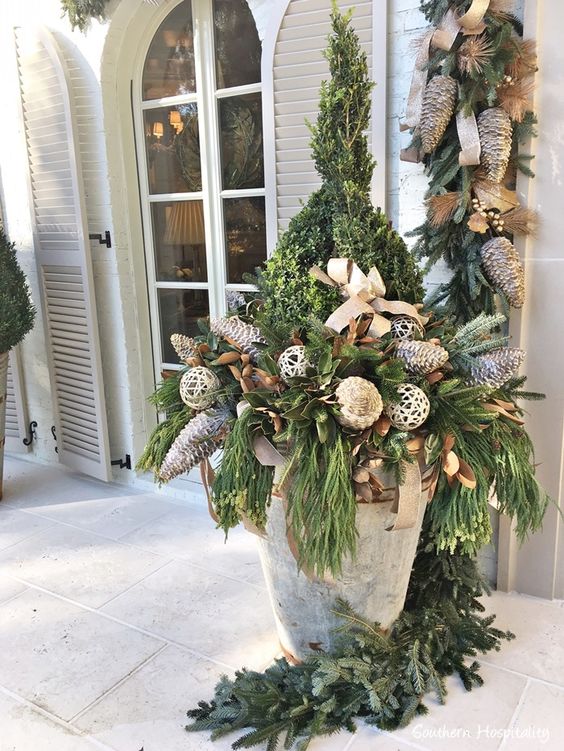 Gorgeous entry to a French country manse (AHL Home for the Holidays showhouse) decorated for Christmas with huge planter filled with greenery and oversized pinecones - Southern Hospitality.