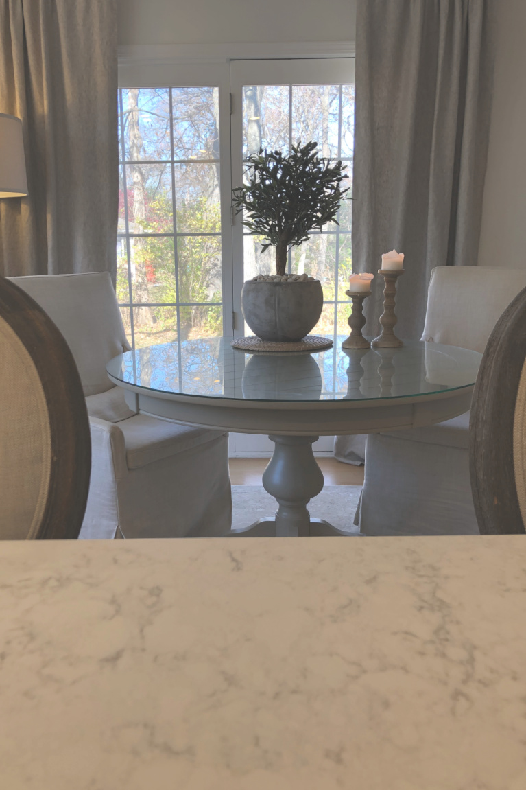 Stunning artificial olive tree in a rustic pale pot (Nearly Natural) on round table in my French country kitchen - Hello Lovely Studio.