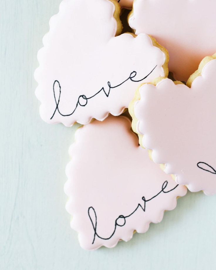 Beautiful scalloped edged heart cookies with "love" by TinyCrumbsCookieCo.