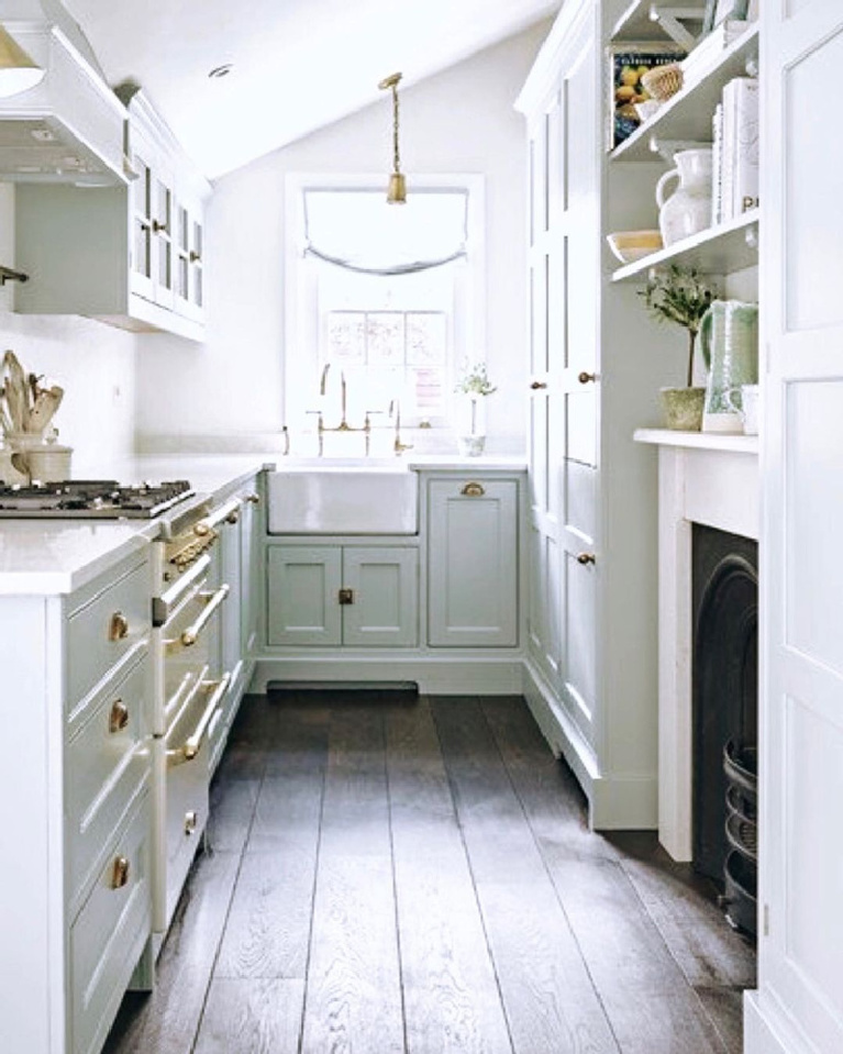 Charming and tiny white French farmhouse cottage style galley kitchen with fireplace and farm sink. #whitefrench #cottagekitchens #tinykitchens #galleykitchen #countrykitchen