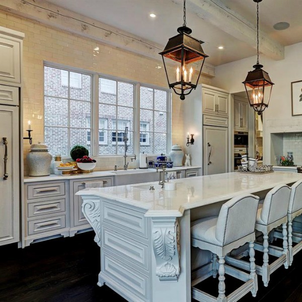 Luxurious white French country kitchen with lantern pendants and white cabinets in a Houston manse by TOH. #frenchcountry #kitchendesign #whitekitchens #elegantdecor