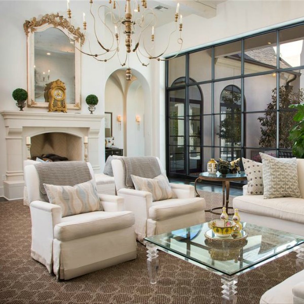 Luxurious white French country living room with black steel windows and French fireplace. #frenchcountry #livingroom #interiordesign #luxuryhome
