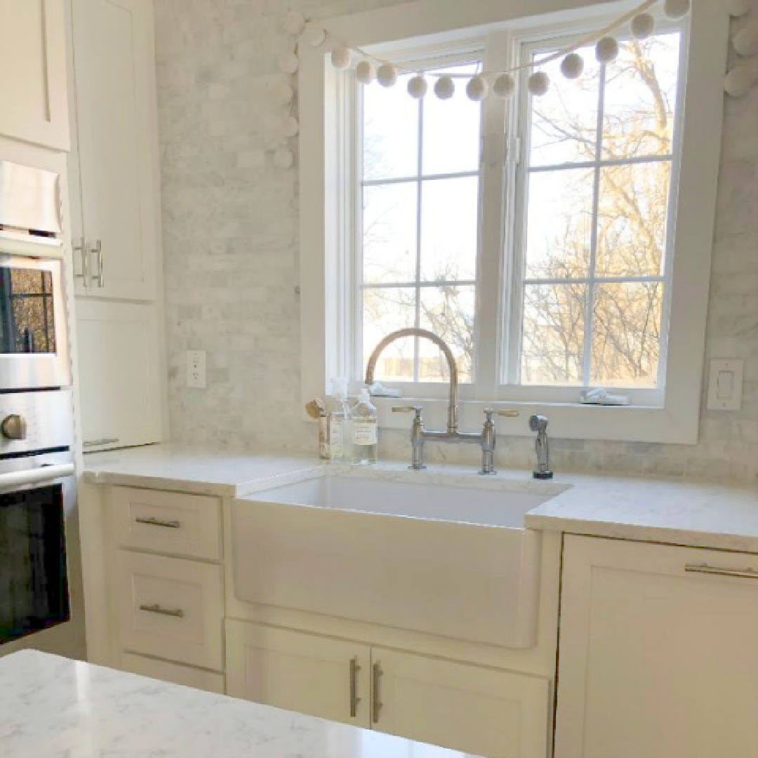 White Shaker kitchen with carrera marble backsplash and Viatera Minuet white quartz counters along with farm sink - Hello Lovely Studio.