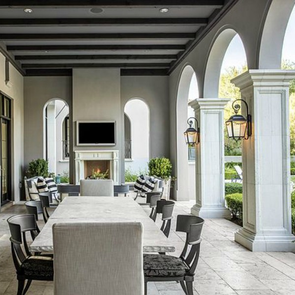 Beautiful loggia with archways, lanterns, dining table and fireplace at a French country Scottsdale home.