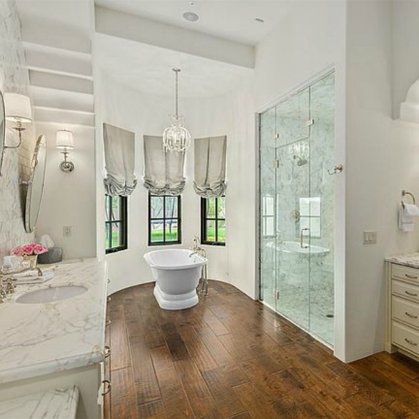 Luxurious and sophisticated white marble French inspired bathroom with freestanding tub and warm wood flooring. #luxuriousbathroom #bathroomdesign #frenchcountry