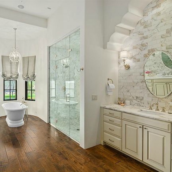 Luxurious and sophisticated white marble French inspired bathroom with freestanding tub and warm wood flooring. #luxuriousbathroom #bathroomdesign #frenchcountry