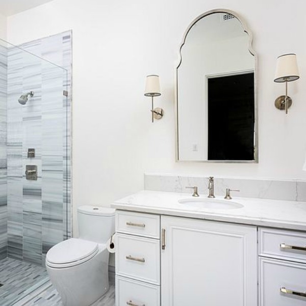 Classic white bathroom with white vanity and French inspired mirror and sconces. #whitebathroom #frenchcountry #bathroomdesign