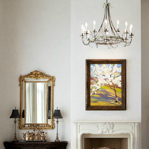 Gilded mirror, crystal chandelier, and French mantel in an elegant Scottsdale home.