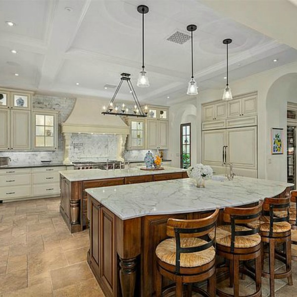 Double islands in elegant French country kitchen in luxurious Scottsdale home with stone floor, two tone cabinets, farm sink, and arch doorways. #luxuriouskitchen #frenchcountrykitchen #elegantdecor #kitchendesign