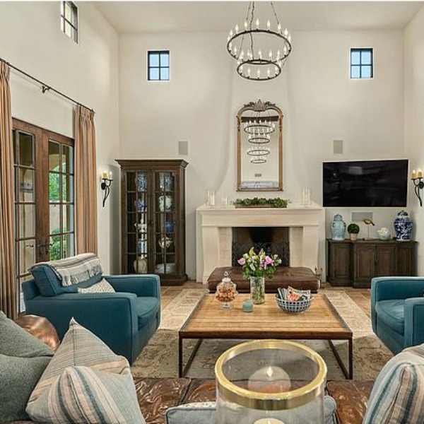 French country great room with brown leather Chesterfield sofa and white kitchen in a luxurious Scottsdale home. #greatroom #interiordesign #luxurioushome