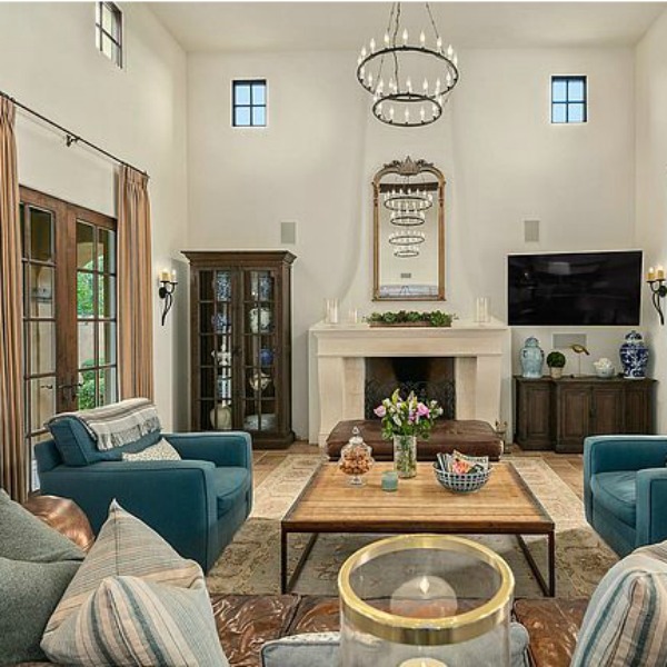 French country great room with brown leather Chesterfield sofa and white kitchen in a luxurious Scottsdale home. #greatroom #interiordesign #luxurioushome 